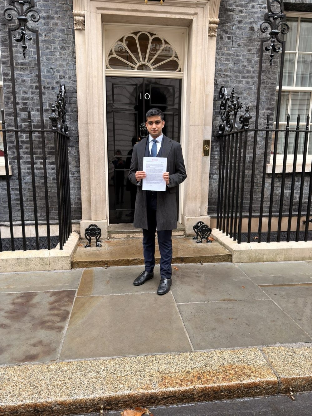 Kiyan Lalani holding a white paper outside 10 Downing Street